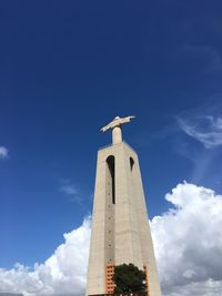 Low angle view of cross statue against cloudy sky