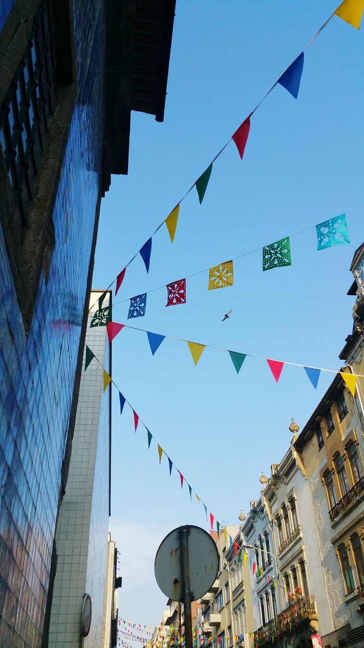 built structure, architecture, building exterior, low angle view, building, multi colored, sky, bunting, city, no people, hanging, day, nature, flag, decoration, celebration, outdoors, shape, blue, sunlight