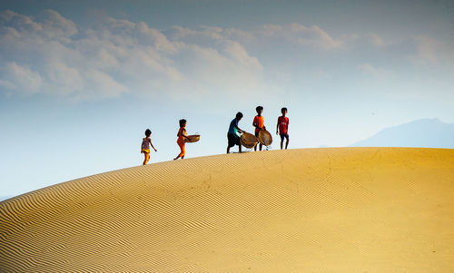 People walking on desert against sky