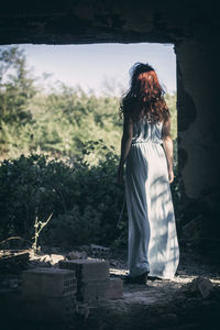 Rear view of fairy young woman standing in front of window