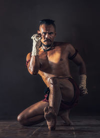 Portrait of shirtless boxer against black background