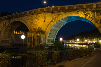 Arch bridge over river against sky at night