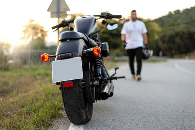 Motorcyclist with helmet in hand goes to chopper