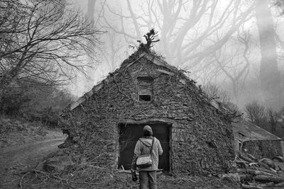 Rear view of man standing by bare tree