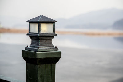 Lantern on wooden post fence against lake