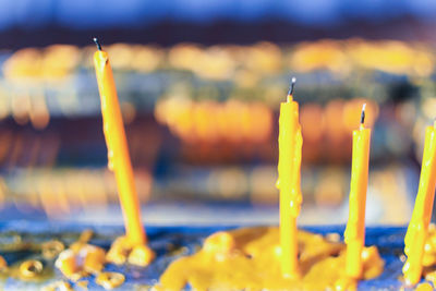 Close-up of yellow candles on temple against building