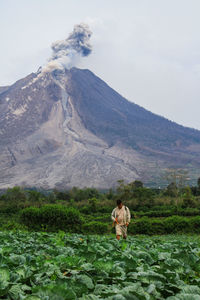 Woman with flowers on mountain against sky