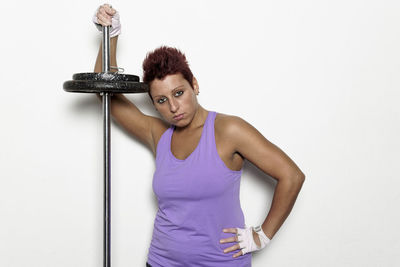 Portrait of young woman standing against white background