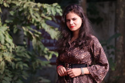 Portrait of young woman standing against plants