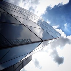 Low angle view of modern building against cloudy sky