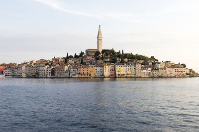 Cityscape by river against sky