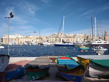 Sailboats moored on harbor in city against sky