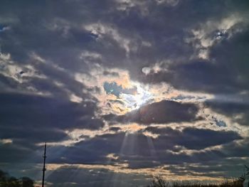 Low angle view of sunlight streaming through clouds