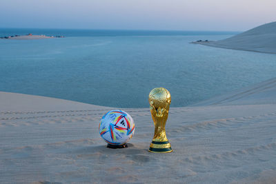 Fifa world cup trophy replica in inland sea qatar with al rihla official match ball of worldcup