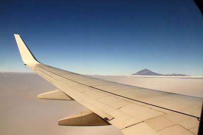 Airplane wing against clear blue sky