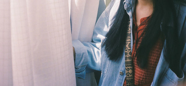 Midsection of woman standing by curtains