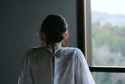 Rear view of woman standing against window