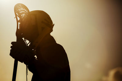 Lacrosse player against sky during sunset