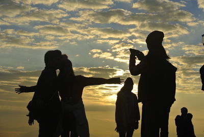 Silhouette people standing against sky during sunset