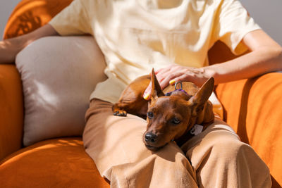 Mature woman sitting in chair with a small dog of the miniature pinscher breed