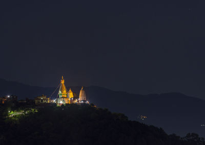 Illuminated buildings in city against sky at night