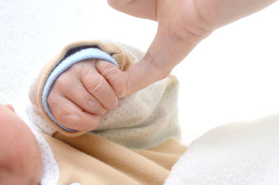 Cropped image of baby holding hand of person