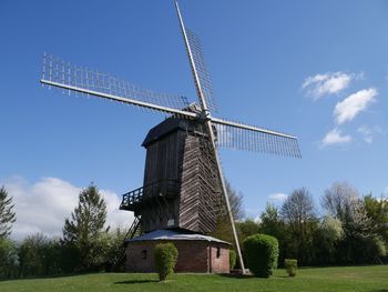 Low angle view of windmill on field against sky