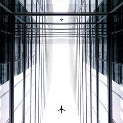 Low angle view of airplanes above tall buildings