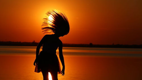 Silhouette woman standing by sea against sky during sunset