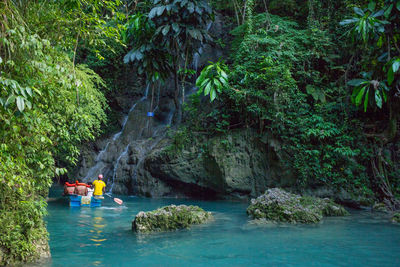 People rowing boat by waterfall