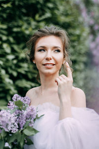 Beautiful bride in a wedding dress walks in a blooming apple-tree park in spring