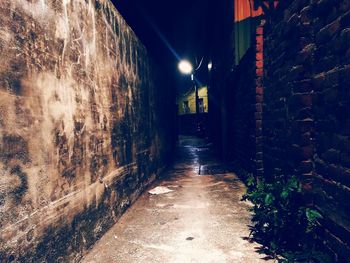 Walkway amidst illuminated buildings at night