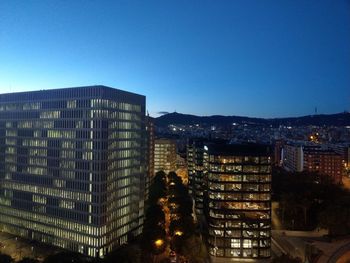 Illuminated buildings against clear sky at night