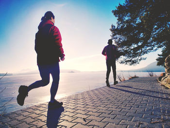 Heterosexual couple run in sun at dock of lake. happy people do sports together, condition training.