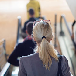 Rear view of woman standing on escalator outdoors