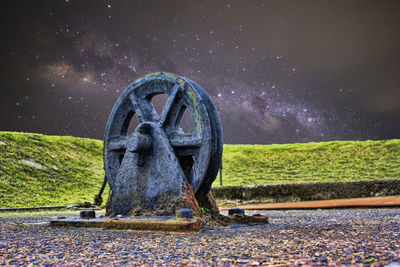 Old metal structure on field against sky at night