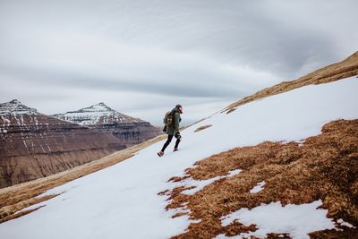 Man walking on snowcapped mountain during winter