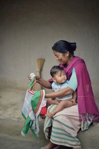 Woman with toddler granddaughter sitting against wall