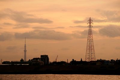 Cranes in city against sky during sunset