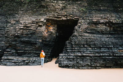 Rear view of woman standing by cave