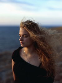 Beautiful woman standing at beach against sky