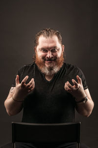 Portrait of man standing against black background