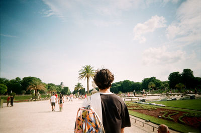 Rear view of people sitting on road against sky