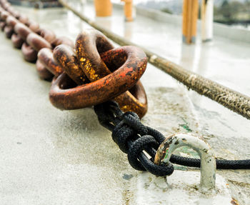 Close-up of rusty chain tied up on metal