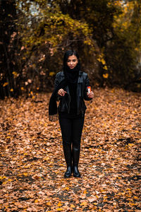 Full length of young woman standing on street during autumn