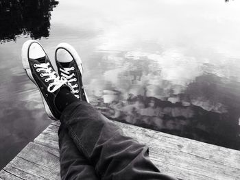 Low section of man sitting by lake