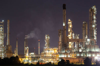 Illuminated factory against sky at night