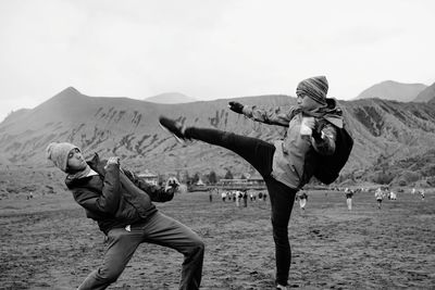 People on field by mountain against sky