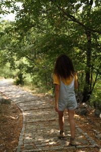 Rear view of woman walking on footpath in forest