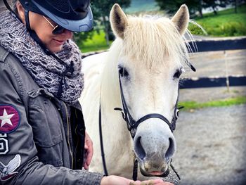 Close-up of woman wearing helmet feeding horse